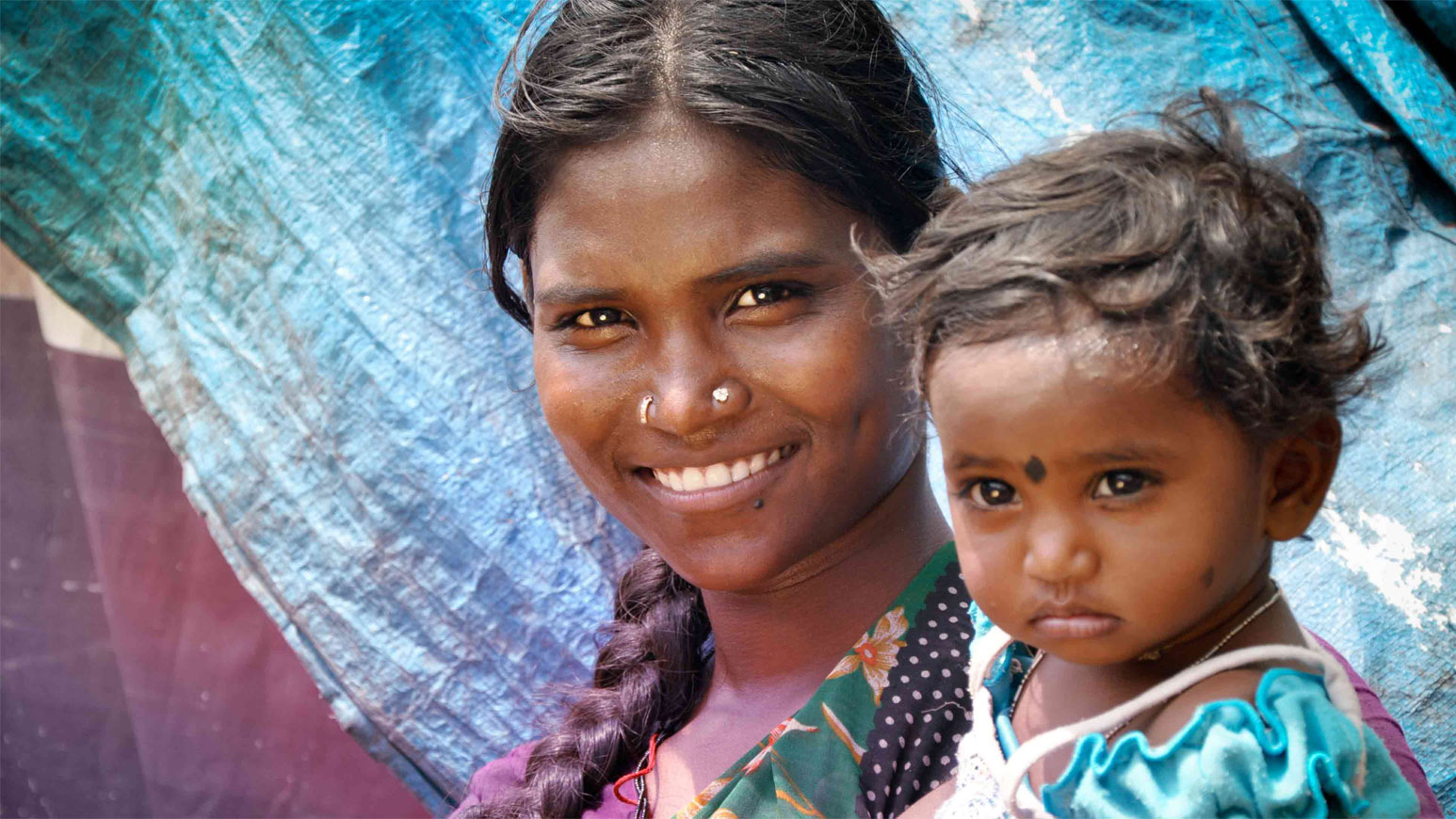 a woman smiles while holding a healthy child  