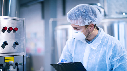 A man in a lab coat and face mask inspecting equipment